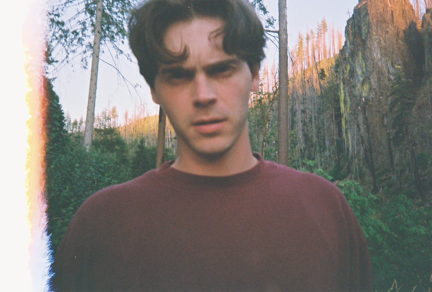 Conner Schultz standing in a forest at sunset.